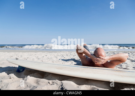 Surfer giacente sulla tavola da surf in spiaggia Foto Stock