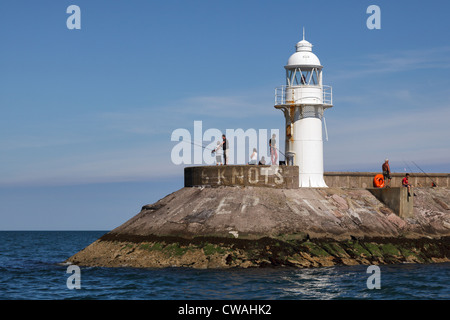 Persone di pesca vicino al faro a Brixham Harbour Foto Stock