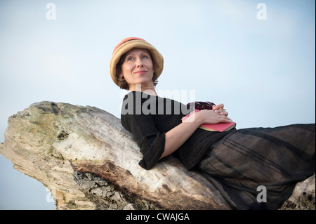 Donna sdraiata sulla driftwood Foto Stock