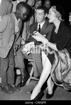 Un giovane fan ottiene gli autografi di Joe DiMaggio e Marlene Dietrich a Sugar Ray Robinson lotta in New York, 1951. La cortesia: Foto Stock