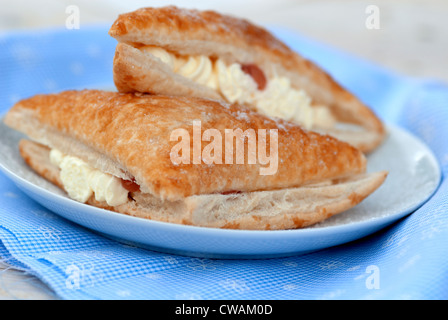 La crema bun contro un gingham blu sullo sfondo Foto Stock