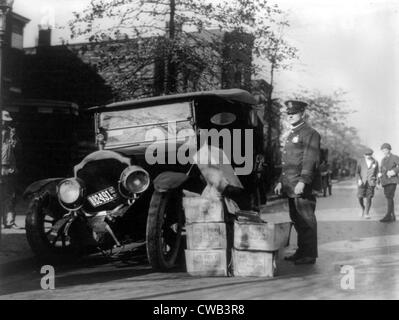Divieto, un poliziotto in piedi accanto ad un auto disastrate e casi di moonshine, 16 novembre 1922. Foto Stock