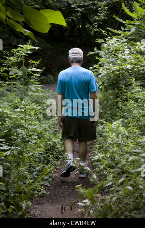 70 anni Pensionati uomo cammina lungo un percorso in Prospect Park di Brooklyn, New York. Foto Stock
