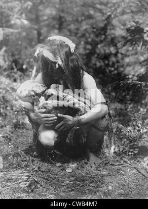 Il Kwakiutl uomo, accovacciata, cullano mummia legato in posizione fetale, titolo: preparare da mangiare la mummia", fotografia di Edward S. Foto Stock
