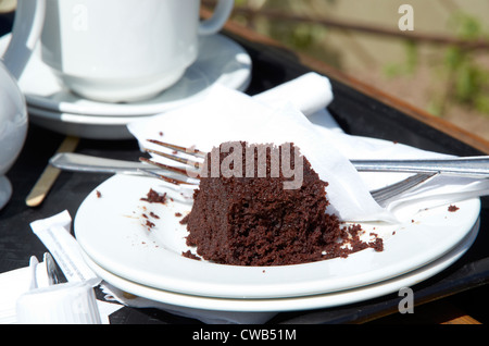 I detriti di un tè del pomeriggio con uneaten torta al cioccolato. Foto Stock