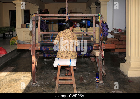 Un processo di tessuti ikat mostrando la tessitura. Tessitura su un footloom. Foto Stock