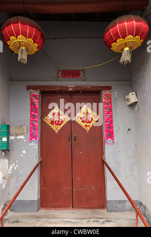 Cinese tradizionale porta con lanterne rosse e buona fortuna segni nella restaurata hutong - Distretto di Wudaoying a Pechino in Cina Foto Stock