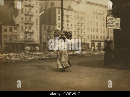 Donna italiana trasporto pesante pacchetto di abbigliamento sul suo capo vicino a Astor Place, New York City. Ella farà cucire i vestiti a casa Foto Stock