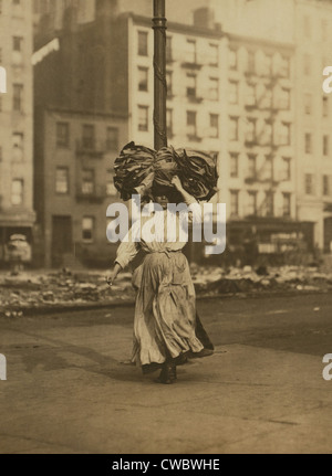 Donna italiana trasporto pesante pacchetto di abbigliamento sul suo capo vicino a Astor Place, New York City. Ella farà cucire i vestiti a casa Foto Stock