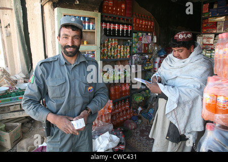 Polizia nazionale afgana officer negozi presso un negozio in ora Zad provincia di Helmand in Afghanistan. I residenti hanno restituito dopo il Foto Stock