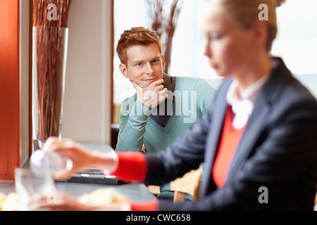 Uomo che guarda un imprenditrice avente il cibo in un ristorante Foto Stock