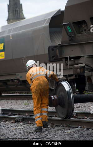 Operaio ferroviario lavorando su di un convoglio in un deposito di merci in Inghilterra. Foto Stock