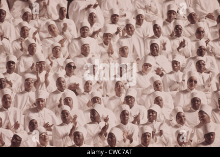 Nero donne musulmane vestite di bianco applaudire Elia di Maometto Salvatore annuale Giornata del messaggio. Marzo 1974. Foto Stock
