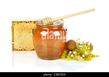 Il dolce miele nel vasetto di vetro con il miele in legno gocciolatore, fresche miele nel pettine e bouquet di fiori selvatici Foto Stock