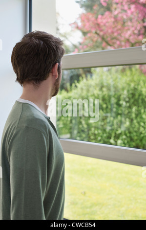 Uomo che guarda attraverso una finestra Foto Stock