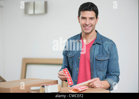 L'uomo sticking 'Fragile' adesivo in scatole di cartone Foto Stock