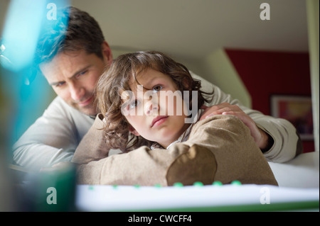 Il pensiero del ragazzo mentre studiava con suo padre a casa Foto Stock
