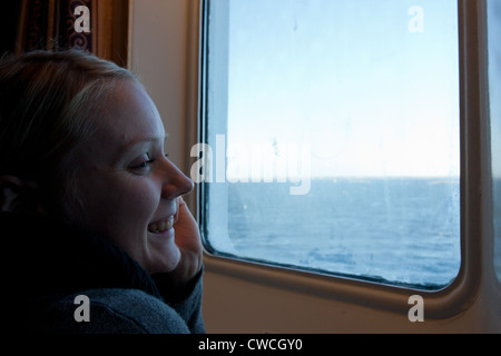 Sorridenti donna gode di una vista dalla nave da crociera cabine al mare Baltico - da Helsinki a San Pietroburgo Foto Stock