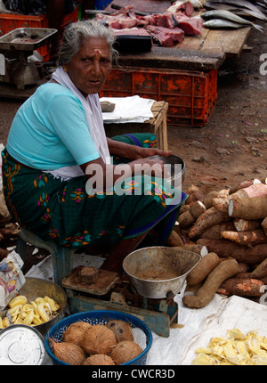 Il vecchio villaggio di età le donne che vende le verdure su strada avente il cibo dal suo ristorante Tiffin box nelle vicinanze di un pesce aperto shop a Kerala India Foto Stock