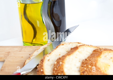 Fette di pane su un tagliere con coltello e olio e aceto. Foto Stock