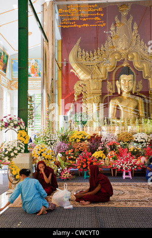 Myanmar Birmania. Giovani monaci nel santuario buddista a Zayar Thein Gyi Monastero, vicino a Mandalay. Statua di Buddha all'interno del contenitore di vetro. Foto Stock