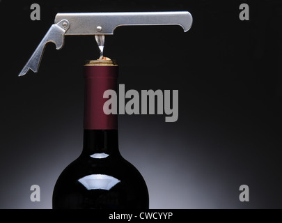 Primo piano di un metallo camerieri cavatappi in una bottiglia di vino. Formato orizzontale su una luce di sfondo grigio scuro. Foto Stock