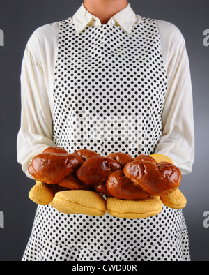 Primo piano di una massaia in un grembiule e guanti da forno tenendo una focaccia appena cotta di challah pane. Foto Stock