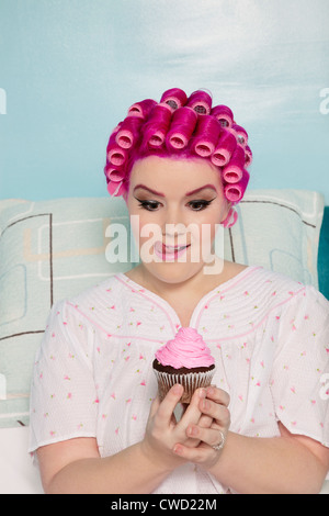 Tentati donna che guarda la tortina Foto Stock