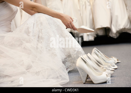 Sezione bassa di donna seduta con varietà di calzature in boutique nuziale Foto Stock