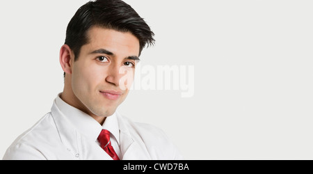 Close-up verticale di un bel maschio indiano medico sorridente su sfondo grigio chiaro Foto Stock
