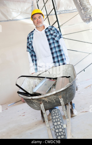 Maschio lavoratore edile in piedi con una carriola Foto Stock