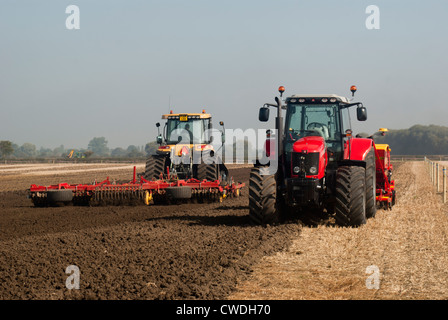 Due trattori l'aratura e la semina in un campo Foto Stock
