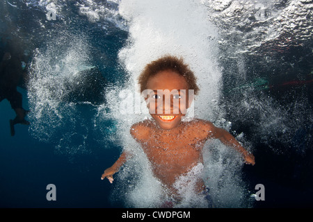 Un giovane Solomon Islander immersioni subacquee nei pressi di un villaggio dove vive. Isole della Florida, Isole Salomone, Oceano Pacifico. Foto Stock