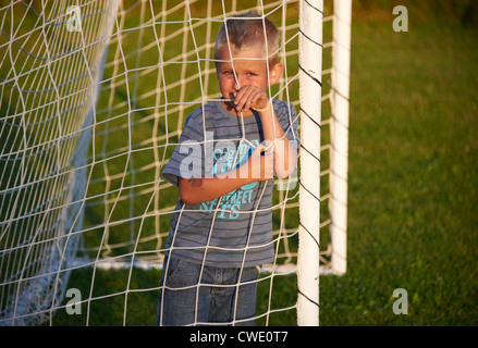 Bambino ragazzo biondo a giocare il gioco del calcio (soccer) sul campo estate Foto Stock
