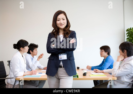 Imprenditrice in piedi di fronte a un tavolo per riunioni Foto Stock