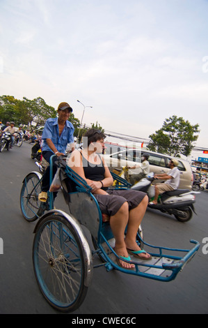 Ritratto verticale di un turista occidentale di equitazione in un ciclo rickshaw attraverso strade trafficate del Vietnam. Foto Stock
