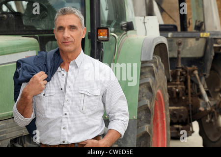 Agricoltore in posa di fronte al suo trattore Foto Stock