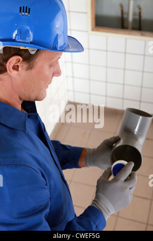 Plumber holding tubo in plastica Foto Stock