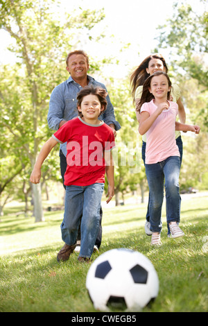 Famiglia giocando a calcio in posizione di parcheggio Foto Stock