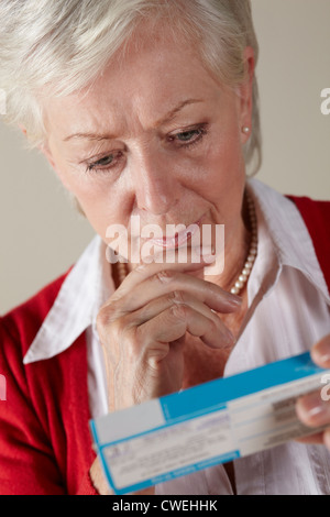 Senior donna che guarda la prescrizione dei farmaci pack Foto Stock