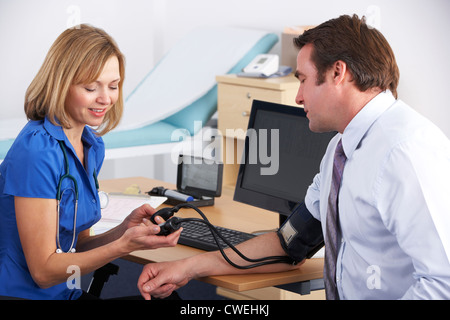 Regno Unito medico tenendo pressione del sangue del paziente Foto Stock