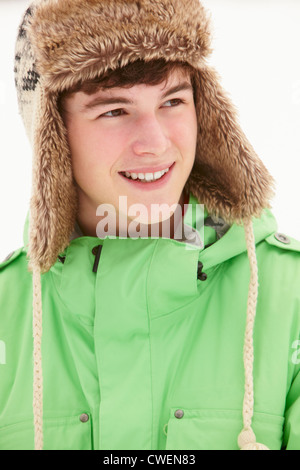 Ritratto di ragazzo adolescente nella neve indossando cappello di pelliccia Foto Stock