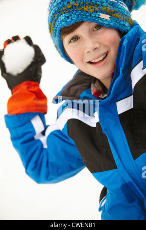 Giovane ragazzo in procinto di lanciare palle di neve indossando Cappellino Foto Stock