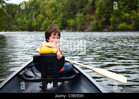 Sorridente ragazzo su una canoa in un lago Foto Stock