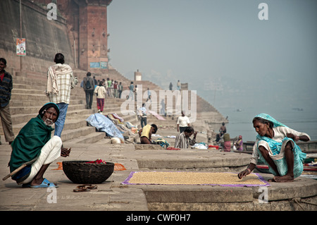 Una coppia di anziani si asciuga i semi al sole in un ghat, Varanassi, India Foto Stock