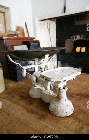 Vecchia cucina bilance di pesatura in una cucina rustica con un Coal Fired grata in background Foto Stock