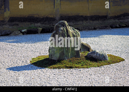 Moss rocce coperte in giardino zen circondato da ghiaia rastrellata Foto Stock