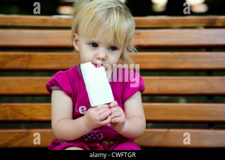 Un anno di età bambina a mangiare il gelato al parco Foto Stock