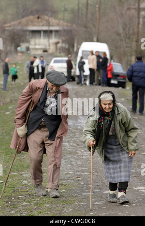 Una donna vecchia e un uomo vecchio a piedi curvò su una strada rurale Foto Stock