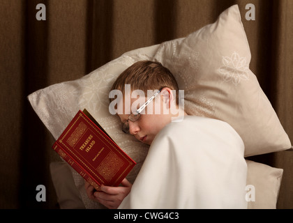 Un ragazzo di 12 a 13 anni di vecchio ragazzo, posa su dei cuscini con un foglio su di lui mentre la lettura "l'isola del tesoro". Il libro non è mio diritto d'autore Foto Stock